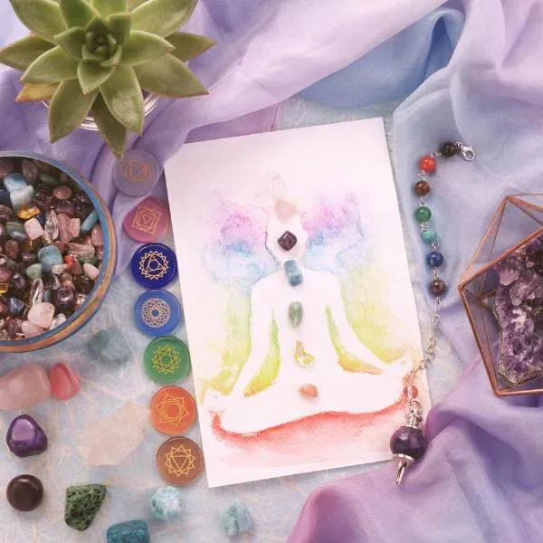 Pierres des chakras, pendule et silhouette en méditation peinte à l'aquarelle